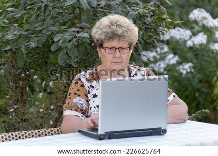 elderly woman working on  a computer in the garden