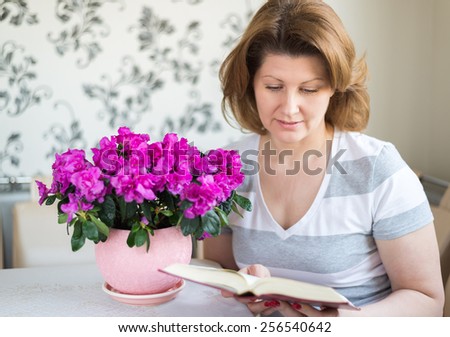 Woman reading a book while sitting at a table