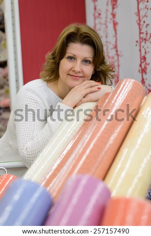 A Woman buys wallpaper in the store