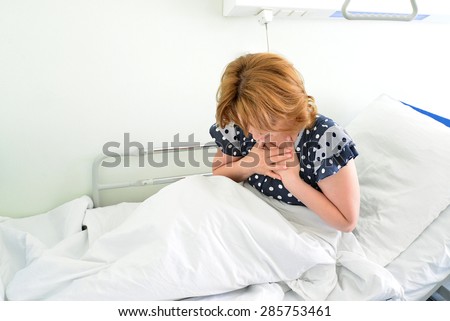 Female patient With heartfelt pain lying on a bed in hospital ward