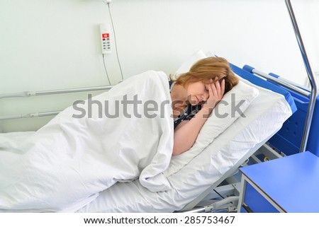 Female patient lying on a bed in hospital ward