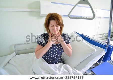 Female patient with angina on a bed in hospital ward