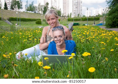 Two female students with a laptop in the park
