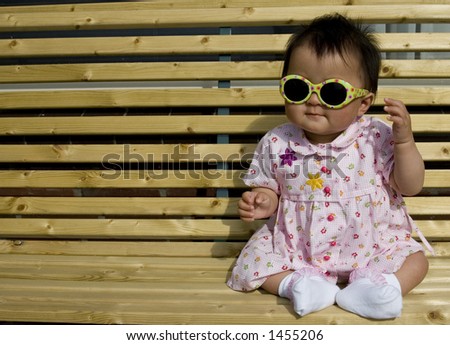 sweet baby girl sitting on a the porch wearing sunglasses