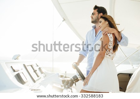 Attractive couple on a yacht enjoy bright sunny day on vacation