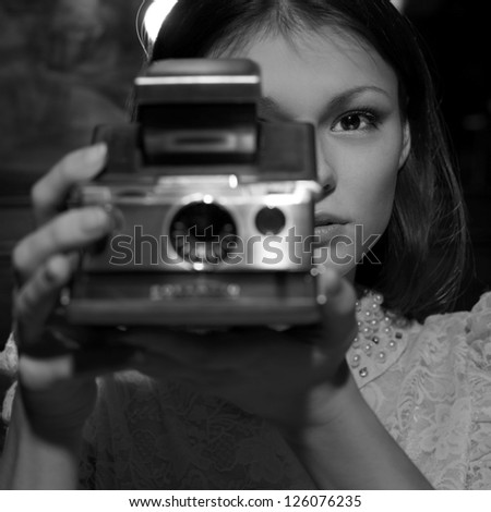 Retro looking young beautiful woman holding a vintage retro camera.