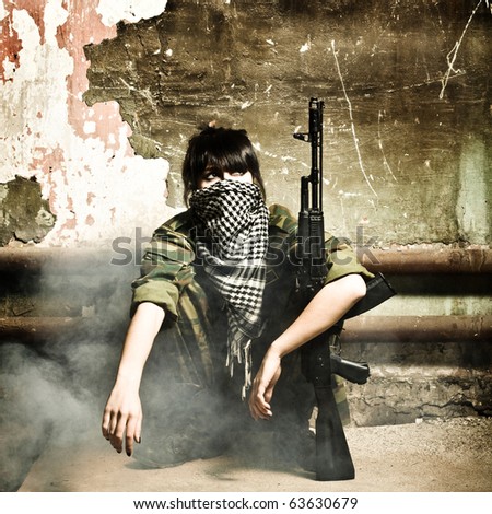 The armed Arabian woman terrorist against old wall studio photo shooting