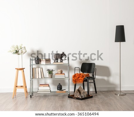 white wall black chair with vase of flower and trinket