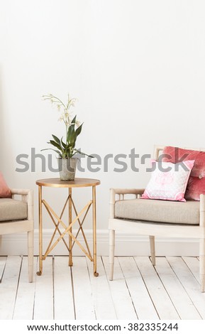 classic armchair  pillow and gold coffee table vase of flower with wooden floor\
behind white wall interior style