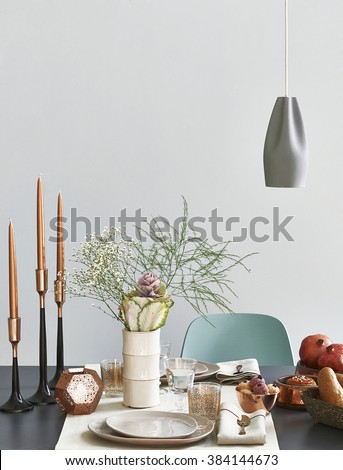 modern dining table setting green chair behind grey wall with vase of flower