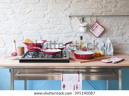 modern red kitchen behind brick wall with red cookware set