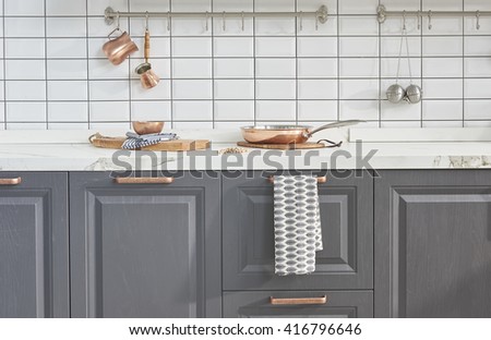 Kitchen brass utensils, chef accessories. Hanging copper kitchen with white tiles wall
