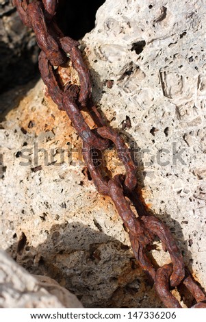 Old industrial chain links in stones at the harbor