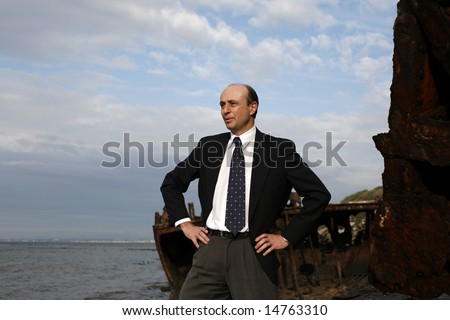 Image of a business man in a strong pose on the wreck of a ship.