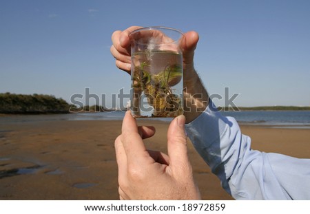 Image of two hands holding on to a glass beaker with an environmental sample