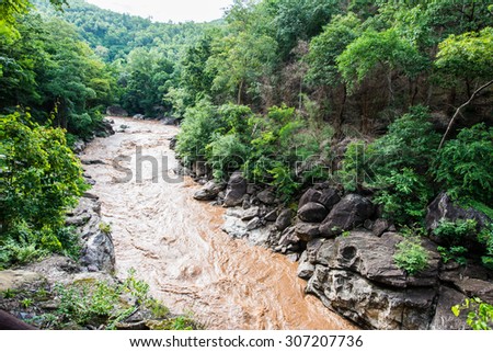 Brown water flowing with wooden walkway in Ob Luang national park, Thailand.