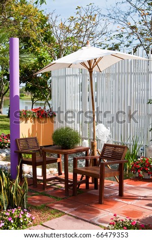 Wooden furniture covered by umbrella  in garden , Thailand.