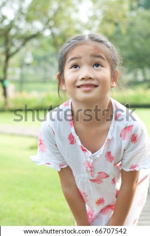 Portrait of lovely asian girl in white suit at public park, she turn the face upwards,Thailand.