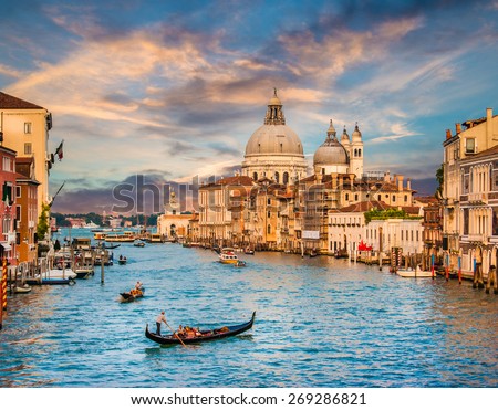 Panoramic view of traditional Gondola on famous Canal Grande with Basilica di Santa Maria della Salute in beautiful golden evening light at sunset in Venice, Italy