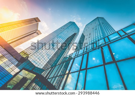 Bottom wide angle view of modern skyscrapers in business district in beautiful evening light at sunset with monochrome retro vintage Instagram style filter and lens flare effect