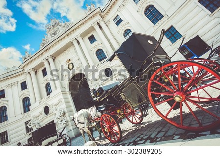 Wide-angle view of famous Hofburg Palace with traditional horse-drawn Fiaker carriages on a sunny day in Vienna, Austria with retro vintage Instagram style grunge filter effect