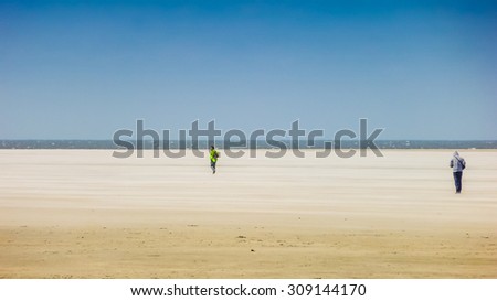 Two people on the way to the sea at a wide and sandy european north sea beach on a sunny day