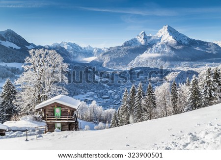 Panoramic view of idyllic winter wonderland mountain scenery with traditional mountain chalet in the Alps on a sunny day with blue sky