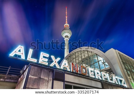 BERLIN - JULY 19: Alexanderplatz neon sign with famous TV tower and train station at night on July 19, 2015 central Berlin Mitte district, Germany.