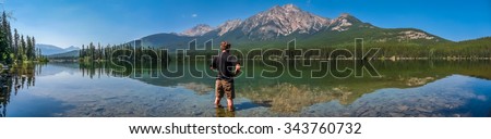 Beautiful panoramic view of lonely man standing in Pyramid Lake with great mountain landscape in the background, Jasper National Park, Alberta, Canada