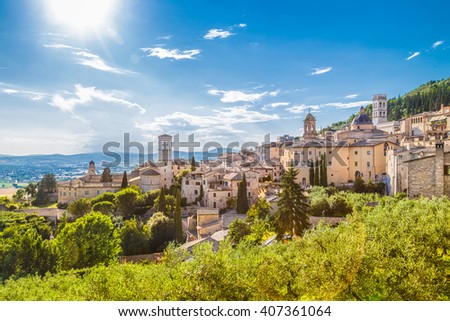 Panoramic view of the historic town of Assisi in beautiful golden morning light at sunrise on a sunny day with blue sky and clouds in summer, Umbria, Italy