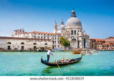 Beautiful view of traditional Gondola on Canal Grande near Piazza San Marco with historic Basilica di Santa Maria della Salute in the background on a sunny day with blue sky in summer, Venice, Italy