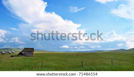Panoramic view of beautiful prairie landscape with old barn and blue sky and clouds in Alberta, Canada