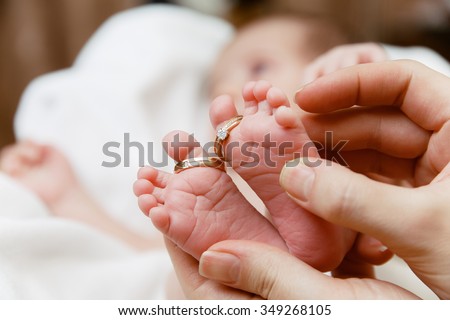 Little baby foots with wedding rings on fingers in mother\'s hands