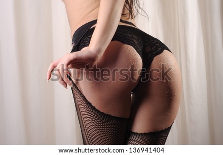 Beautiful buttocks of a woman wearing fishnet stockings, lace panties and suspenders.