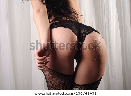 Beautiful buttocks of a woman wearing fishnet stockings, lace panties and suspenders. Passion