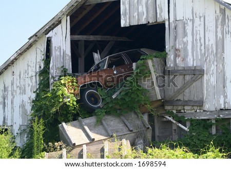an abandoned car hanging out of an abandoned barn