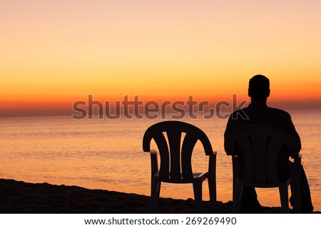 Man sits on chair alone in sunset