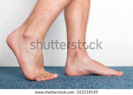 Healthy male feet making a step over home-like background.