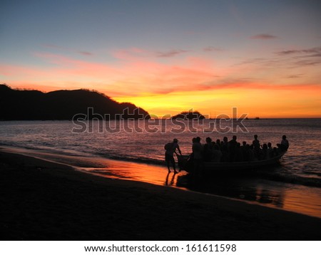 Playas el Coco Sunset. Costa Rica's Playas el Coco at sunset with tour boat coming ashore.