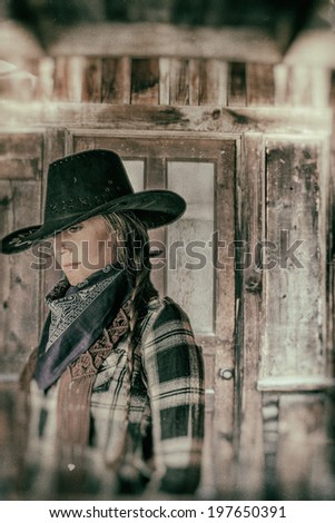 Cowgirl Western Town. Cowgirl with western wooden building door behind her.