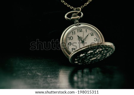 Classic Pocket Watch. An old fashioned looking pocket watch timepiece. shot on black and edited in vintage film style.