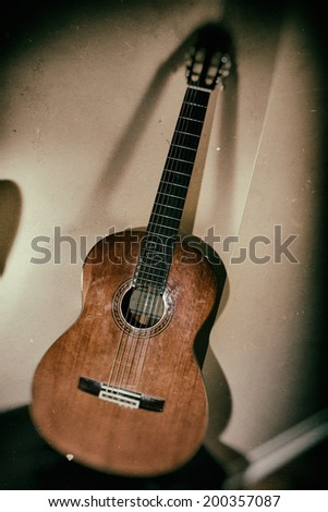 Classical Guitar Leaning Corner. A classical acoustic guitar leaning in a corner, vintage camera effect.