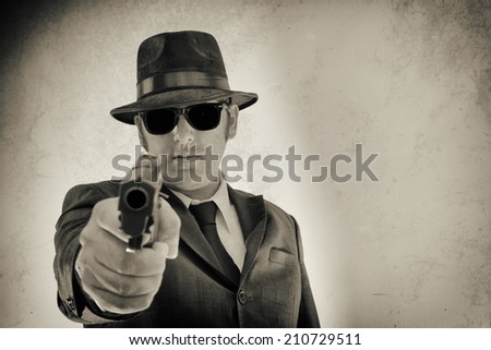 Noir Man Pointing Gun Right Hand. Man in suit, hat and sunglasses pointing a gun at the camera.