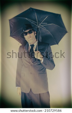 Man Hat Suit Holding Umbrella. Man in suit, hat and sunglasses holding an umbrella.