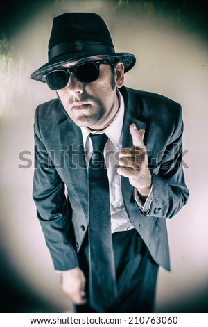Man in Suit Finger Gun Point. Man in suit, hat and sunglasses points a finger gun.