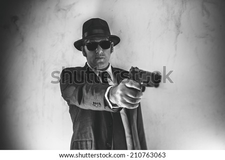 Man in Suit Points Gun. Man in suit, hat and sunglasses points a gun.