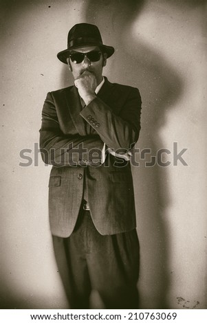 Man in Suit Thinking Classic. Vintage edited image of a thinking man in a suit, hat and sunglasses.