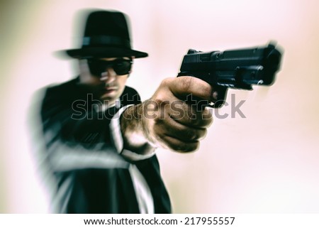 Man in Hat Pointing Gun. Man in suit, hat and sunglasses pointing a gun with action blur.