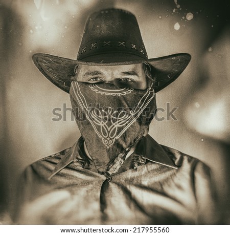 Old West Cowboy Bandit 2. Old west bandit outlaw with covered face and cowboy hat, edited in vintage film style.