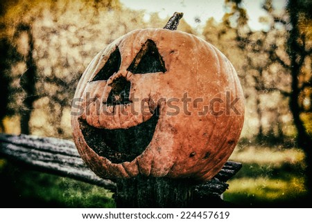 Jack O Lantern 1. A jack o lantern resting on a country fence during the Halloween autumn season. Edited in vintage photography style.